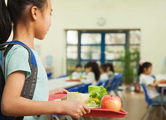 School girl holding food tray in school cafeteria